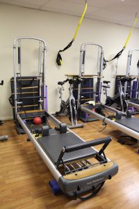 iBeyond Pilates Studio showing Reformer Machine, TRX suspension equipment, and spin bikes.